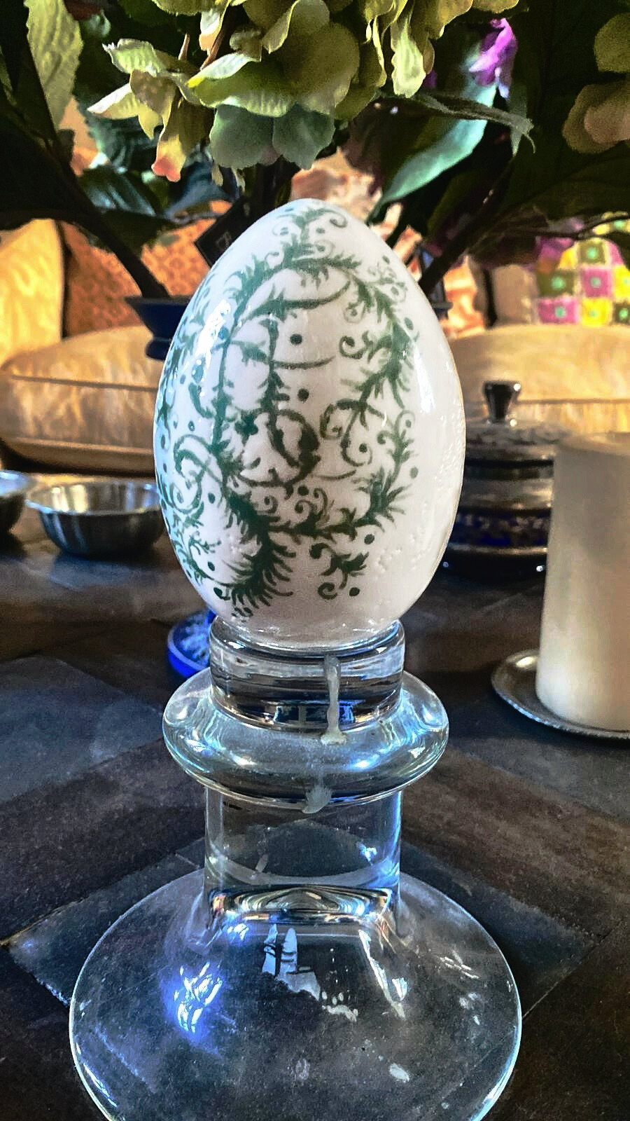 Ceramic egg painted in green, on a glass stand